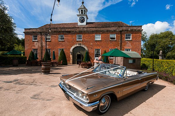 Classic car outside traditional brick building with clock tower.