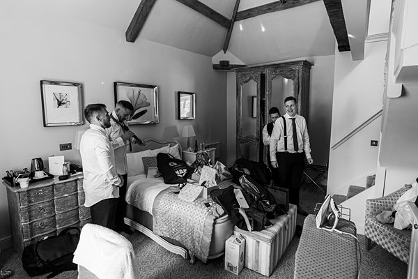 Groom and friends getting ready in a messy hotel room.