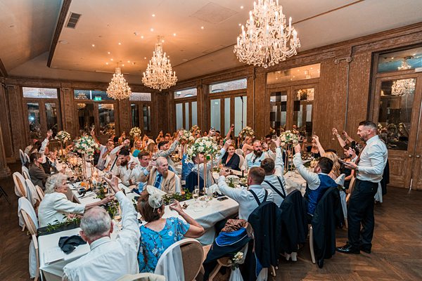 Elegant wedding reception with guests toasting in a hall.