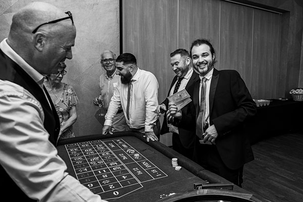 Group playing roulette at casino night, black and white photo.