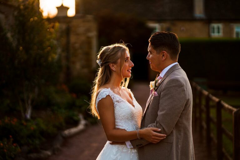 Couple in wedding attire during sunset ceremony.