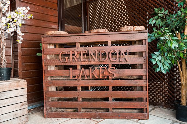 Wooden Grendon Lakes sign with plants.