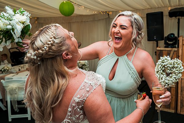Joyful wedding celebration with laughing women and champagne.