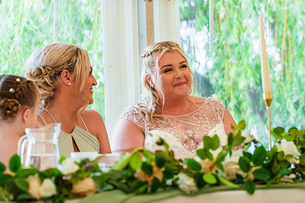 Bride smiling at wedding reception table.