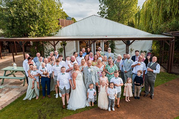 Wedding guests posing outside with bride and groom.