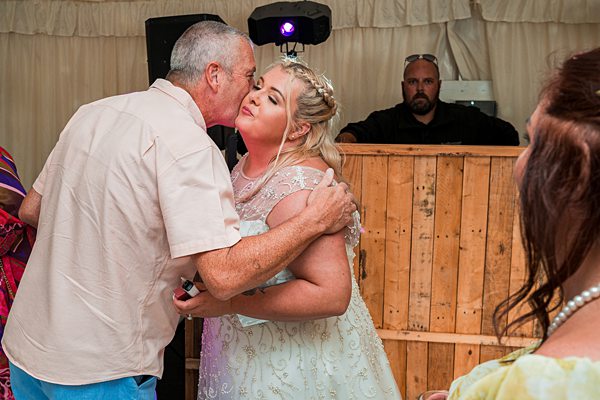 Couple dancing at wedding, DJ in background.