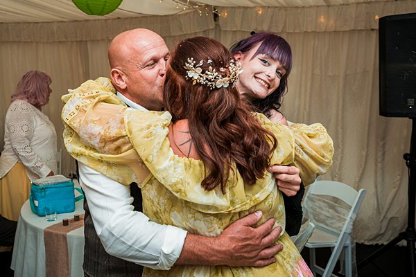 Man and two women hugging at joyful event.