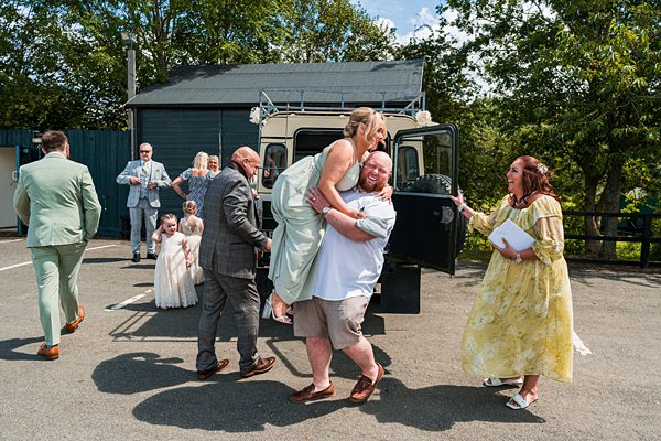 Joyful wedding guests embracing outside.