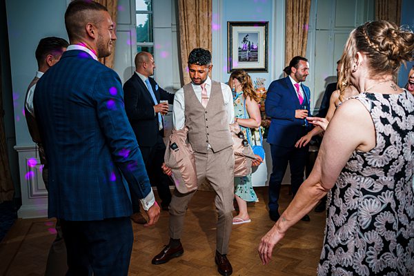 Guests dancing at a lively indoor wedding reception.
