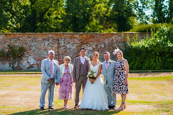 Family wedding photo outdoors in sunshine.