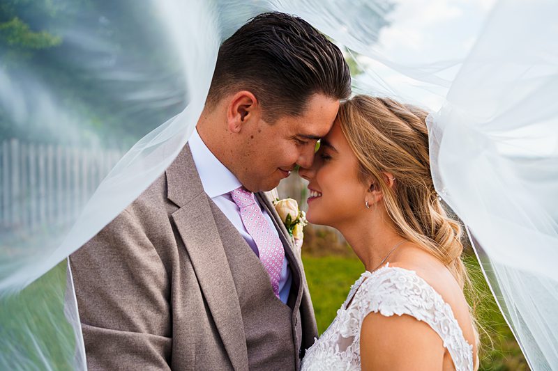 Bride and groom sharing intimate moment under veil