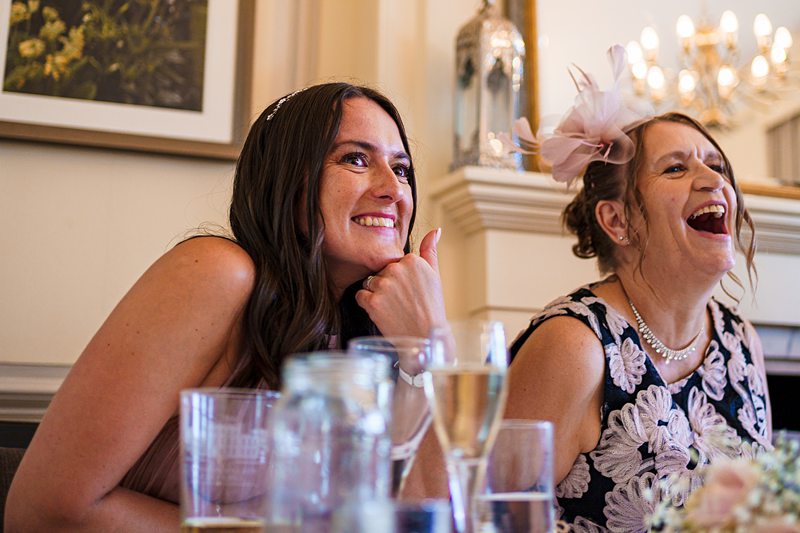 Two women laughing joyfully at a social event.