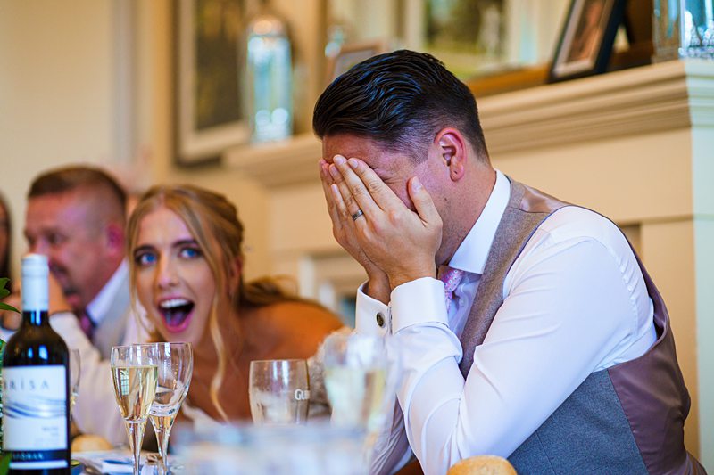 Man facepalms, woman reacts, at dining event.