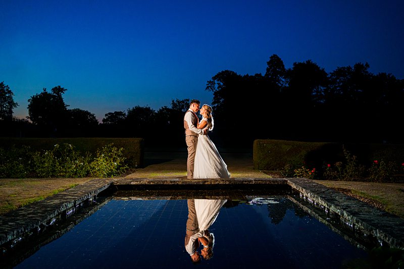 Couple embracing at dusk with reflective pool.