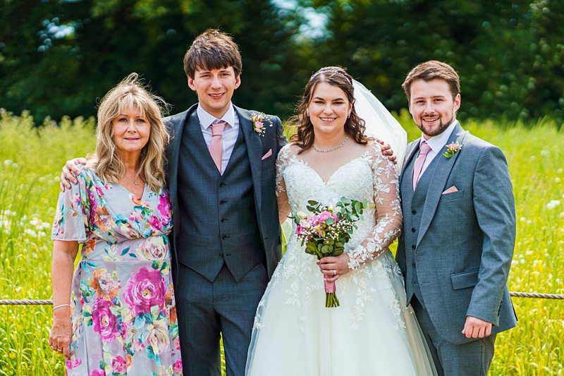 Family wedding photo outdoors with bride and groom.