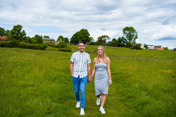 Couple walking in green meadow, rural UK.