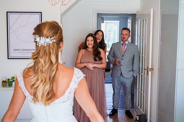 Bride approaching smiling guests indoors at a wedding.