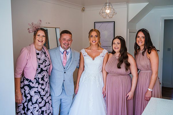 Bride with family in elegant attire smiling indoors.