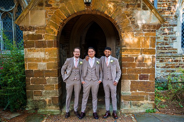 Three men in suits at church entrance.
