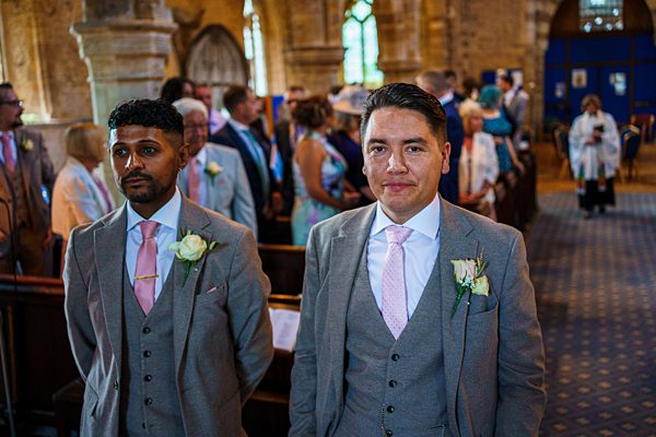 Groomsmen waiting in church at wedding ceremony.