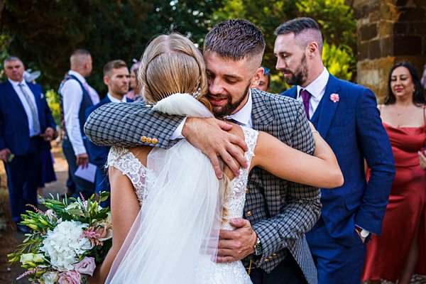 Bride and groom embracing at wedding ceremony.