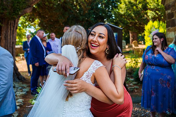 Joyful wedding hug outdoors with guests.