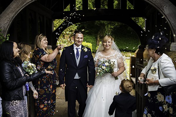 Bride and groom smiling with confetti at wedding