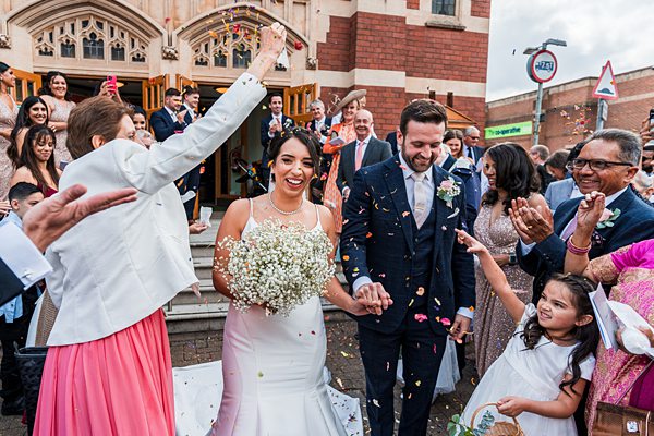 Joyful wedding confetti toss outside church.