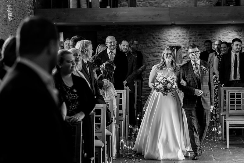Bride walking aisle with father at wedding ceremony.