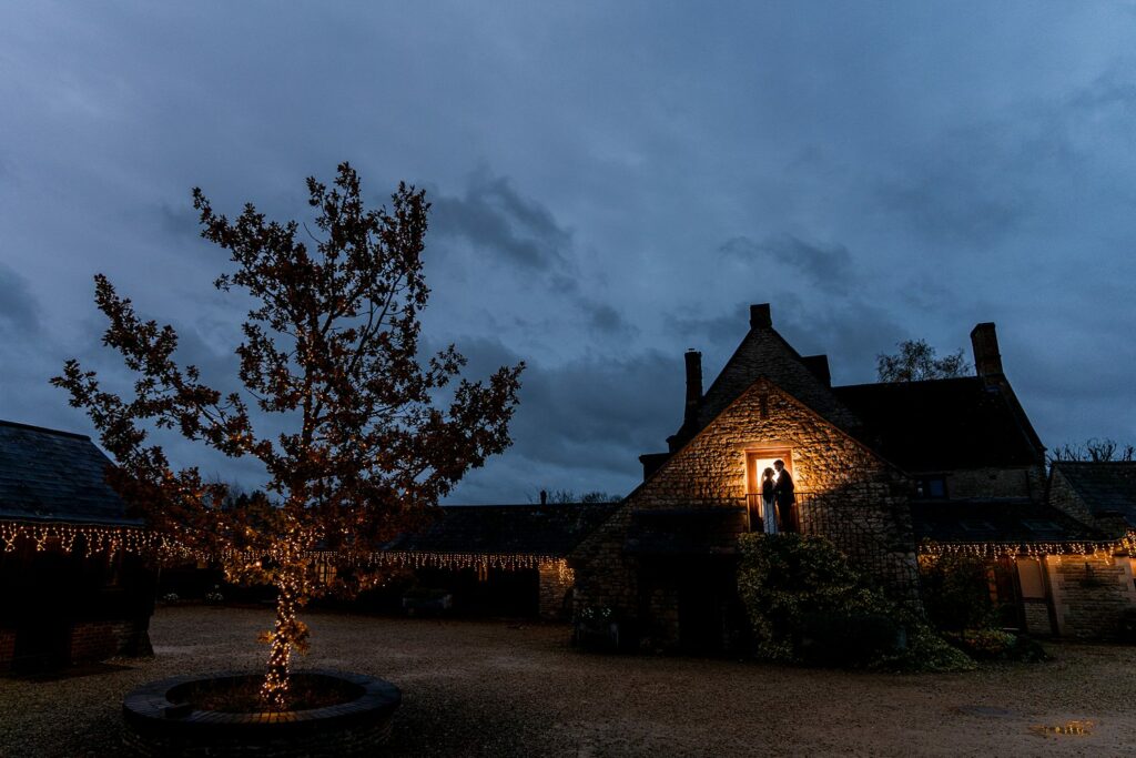 Twilight at illuminated rustic cottage with fairy lights.