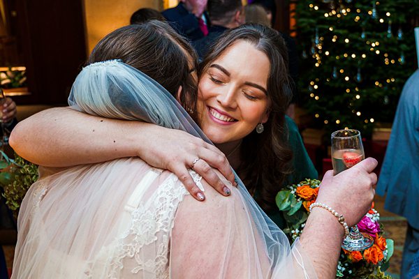 Bride hugging guest at festive wedding reception.