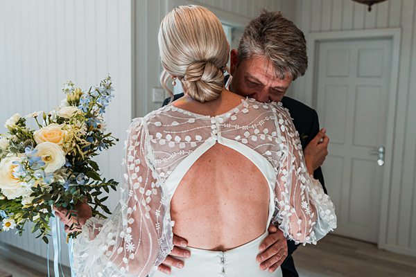 Bride in lace dress embracing groom with bouquet