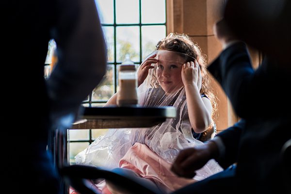 Child in dress playing with veil indoors.