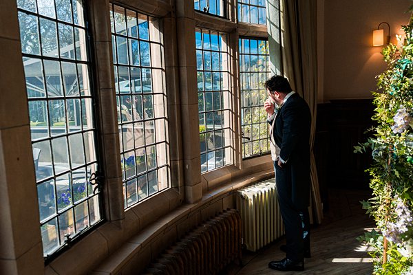 Man in suit contemplating by vintage window.