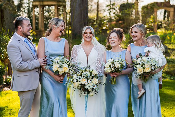 Bridal party smiling outdoors at wedding ceremony.