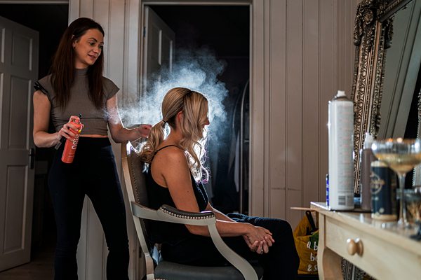 Hairstylist applying hairspray to client in salon.