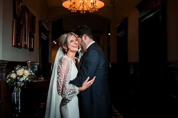 Couple embracing at wedding in elegant hallway.