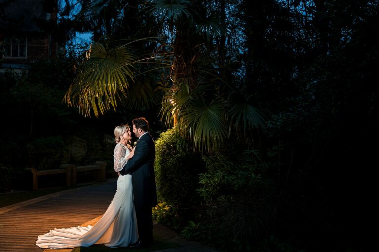 Couple kissing at night, tropical garden setting.