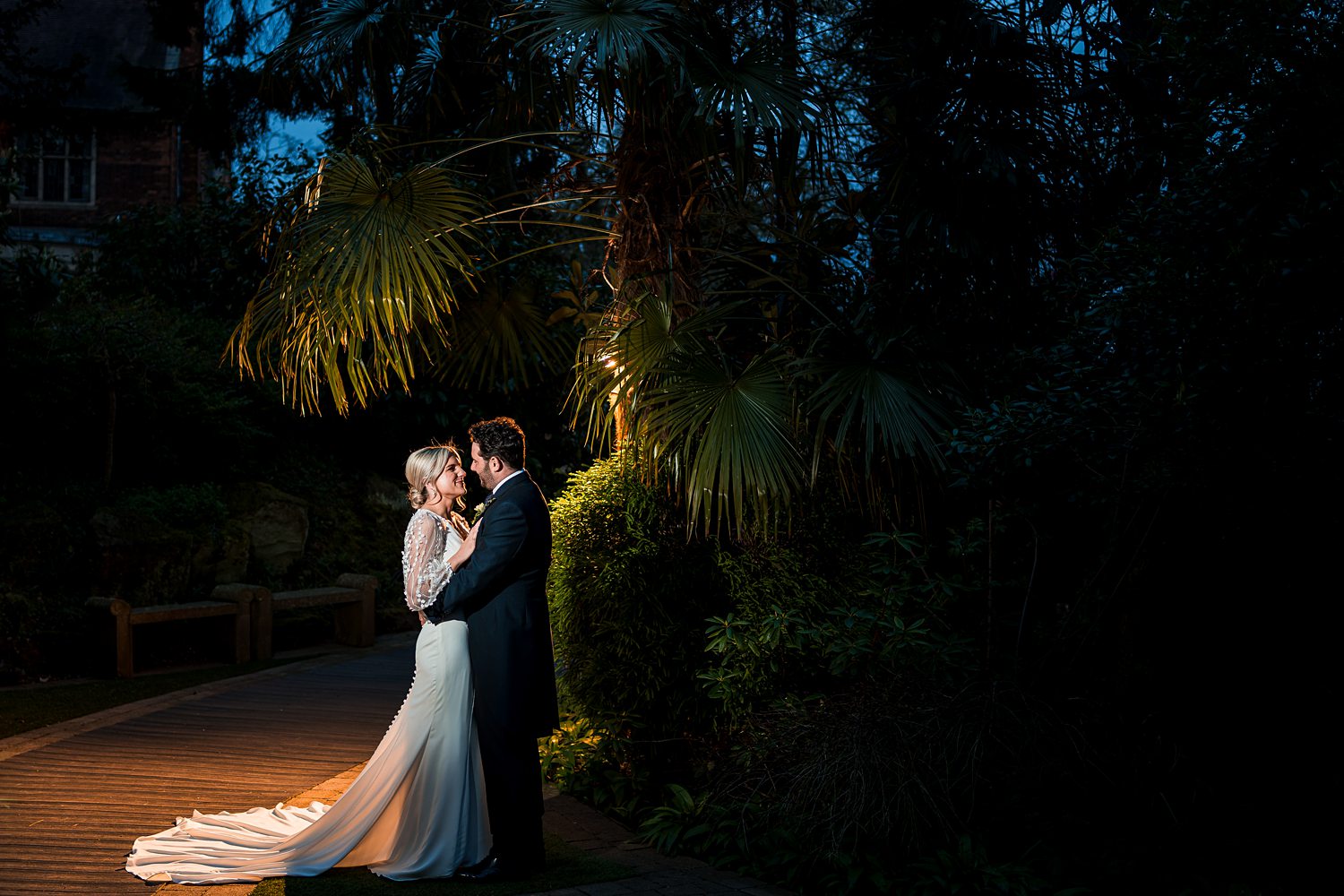 Couple kissing at night, tropical garden setting.