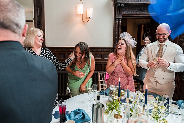Joyful wedding guests laughing at reception table.