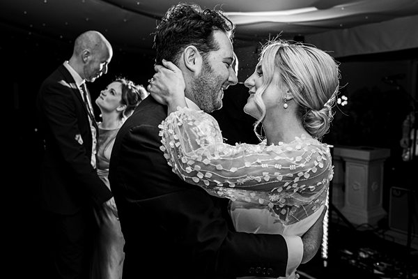 Two couples dancing at wedding reception in black and white.