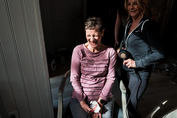 Woman laughing indoors, friend in background.
