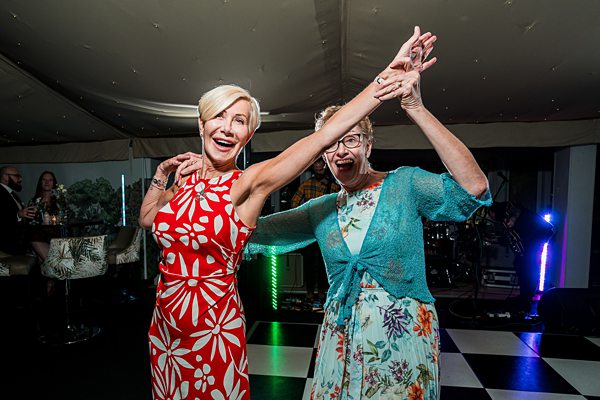 Two women dancing joyfully at festive event.