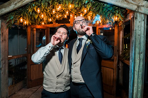 Two men in suits smoking cigars at night event.