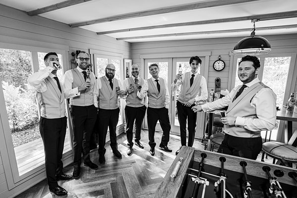 Groomsmen toasting in elegant attire indoors.