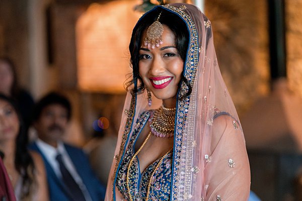 Bride in traditional Indian wedding attire smiling.