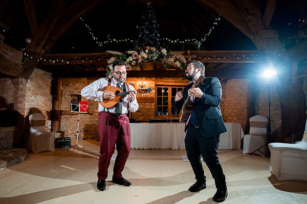 Two men performing music at evening wedding reception.