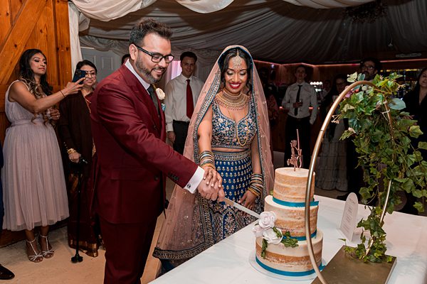 Couple cutting cake at traditional wedding celebration.