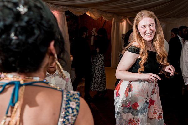 Woman dancing at multicultural wedding reception.