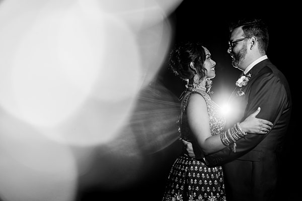 Couple embracing at wedding, black and white, bokeh light.